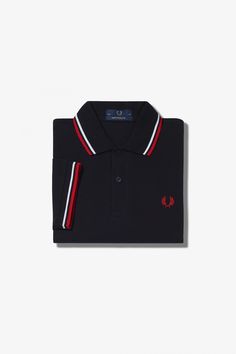 The original twin tipped Fred Perry Shirt. Made by expert hands in Leicester, England and adopting Fred's signature streamlined fit. A piece of British subcultural uniform for 60 years. Made in Leicester, England / Cotton piqué / Boxier fit than the M3600 with smart, flat hem / Twin tipped collar and cuffs / Two button placket COLOR: BLK/WHT/BT.RED Shirt Size S M L XL XXL Chest Size 35-37 38-40 41-43 44-46 47-49 Fred Perry Size 36 38 & 40 42 44 & 46 Classic Short Sleeve Polo Shirt With Striped Cuffs, Classic Short Sleeve Tops With Striped Cuffs, Classic Tops With Polo Collar And Striped Cuffs, Classic Top With Polo Collar And Striped Cuffs, Classic Tops With Striped Cuffs And Polo Collar, Classic Navy Polo Shirt With Contrast Collar, Classic Navy Tops With Contrast Trim, Navy Classic Tops With Contrast Trim, Classic Three-stripes Polo Shirt