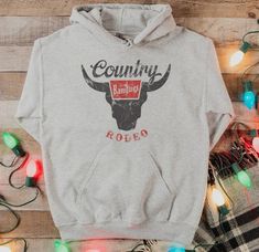 Country Rodeo Hooded Sweatshirt | JQ Clothing Co. Western Hoodies, Rodeo Bull, Western Sweatshirts, Cute Country Outfits, Country Girls Outfits, Western Style Outfits, Cow Shirt, Country Shirts, Online Clothing Boutiques