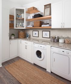 a washer and dryer in a white laundry room with open shelving on the wall