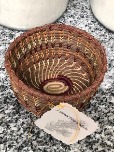 a woven basket sitting on top of a counter next to two white vases and a tag