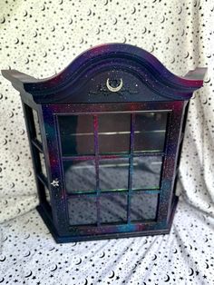 a purple and blue glass case on a white surface with stars, moon and crescents