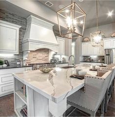 a large kitchen with an island in the middle and two pendant lights hanging from the ceiling