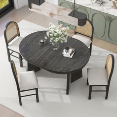 a dining table with four chairs around it and a vase on the table next to it