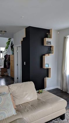 a living room filled with furniture and a black wall behind the couch is an open door