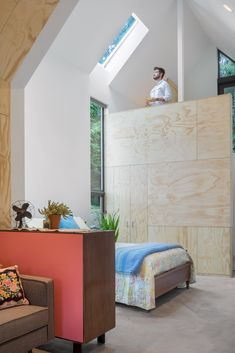 a man standing on top of a bed next to a couch in a living room