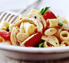 a white plate topped with pasta covered in sauce and vegetables next to a silver fork