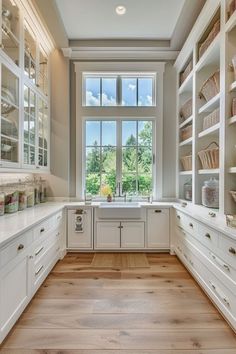 a kitchen with lots of white cabinets and drawers on the wall, along with an open window