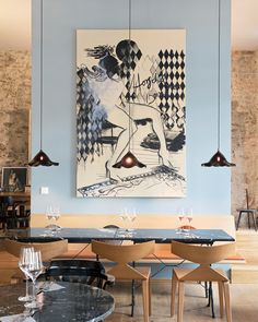 an art piece hangs above the dining table in this modern style restaurant with blue walls and wood flooring