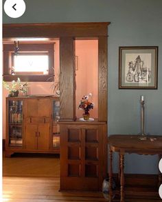 a living room filled with furniture next to a wooden table and book shelf on top of a hard wood floor