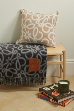 a blanket and some books on the floor next to a wooden chair with a pillow