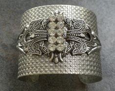 This cocktail bracelet for women is a bangle cuff with rhinestones and is beautiful Art Deco Jewelry. It is adorned with a silver plated brass stamping, a sparkly rhinestone bar. The cuff bracelet is heavy and etched with basket weave designs. The pieces are bolted together securely, and the rhinestone bar is affixed securely with wire in between so it has a 3 dimensional aspect to it. This will adjust to many wrist sizes, although best suited for a medium sized wrist. It is 2 inches wide, and m Adjustable Bangle Cuff Bracelet With Diamond Accents, Adjustable Diamond-accent Cuff Bangle, Adjustable Diamond Accented Cuff Bangle, Glamorous Rhinestone Cuff Bangle Bracelet, Silver Crystal Embellished Bracelet Gift, Silver Crystal Embellished Bracelet For Gift, Adjustable Jeweled Silver Cuff Bracelet, Adjustable Silver Cuff Bracelet With Diamond Accents, Adjustable Silver Cuff Bracelet With Rhinestones