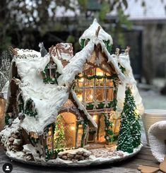 a gingerbread house is decorated with christmas lights and icing on a table outside