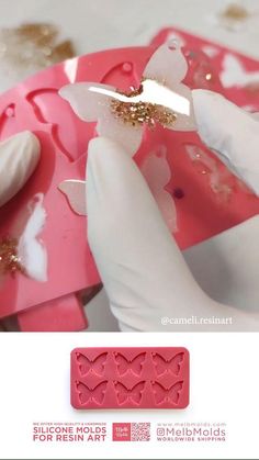 someone cutting out hearts with scissors on top of a pink cake molding sheet that is shaped like a butterfly