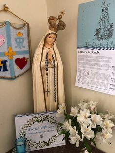 a statue of the virgin mary is next to a notepad and flowers on a table