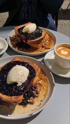 pancakes with blueberry toppings and whipped cream on them are served at an outdoor cafe