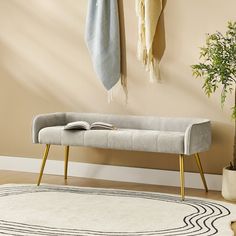 a gray bench sitting on top of a rug next to a potted plant