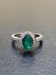 DeKara Designs Collection Our latest design! An elegant and lustrous Colombian Emerald surrounded by beautiful diamonds in a halo setting. Metal- 14K White Gold, .583. Stones- 1 Oval Colombian Emerald 1.25-1.40 Carats, 40 Round Diamonds, F-G color VS clarity, 0.30 carats. Latest of my creations. A beautiful Oval Colombian Emerald Halo Diamond Ring. The Emerald is a beautiful green and it is professionally prong set in between four double prongs. There are ten pave set round diamonds on each side Oval Emerald Ring In 14k White Gold, Elegant Emerald Ring With Halo In Cubic Zirconia, Elegant Emerald Halo Ring With Cubic Zirconia, Elegant Emerald Cubic Zirconia Ring With Halo, Formal Emerald Ring With Halo And Round Cut, Emerald Rings With Diamond White Halo Setting, Formal Emerald Ring With Halo, Formal Emerald Halo Ring With Round Cut, Luxury Round Diamond Emerald Ring With Halo Setting