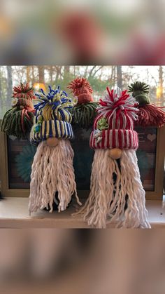 three knitted hats with tassels and bows are sitting on top of a shelf