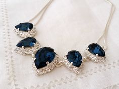 the necklace has three blue stones and is set on top of a white lace doily