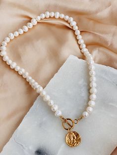 'Chloe' - a modern take on a classic pearl. Beautiful freshwater pearls combined with a gold toggle clasp and a 24k gold coin pendant. Pearls are symbolic of wisdom gained through experience. The gems are believed to offer protection, as well as attract good luck and wealth. Pearls are symbolic of the wearer's loyalty, generosity, integrity, and purity. The surface of the pearls may have few bumps and ridges that indicate the natural origin of the pearls. The necklace is approximately 42 cm in l Gold Pearl Toggle Necklace With Pearl Drop, Gold Toggle Necklace With Pearl Drop, Gold Pearl Drop Toggle Necklace, White Pearl Toggle Necklace With Pearl Pendant, Gold Pearl Toggle Necklace With Pearl Chain, White Pearl Toggle Necklace With Pearl Charm, Gold Pearl Necklace With Toggle Clasp, Classic Gold Pearl Necklace With Toggle Clasp, Gold Toggle Necklace With Pearl Chain