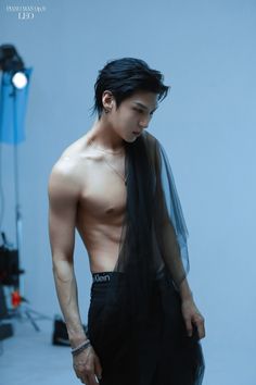 a man with no shirt is standing in front of a blue background and wearing a black scarf