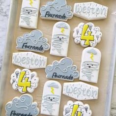 decorated cookies in the shape of clouds and lightnings are on a baking sheet with writing