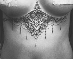 a black and white photo of a woman's stomach with an intricate tattoo on it