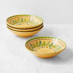 three yellow and green bowls sitting on top of a white counter