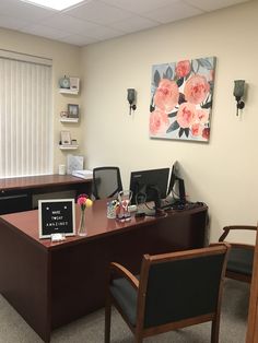 an office cubicle with two desks, chairs and pictures on the wall above them