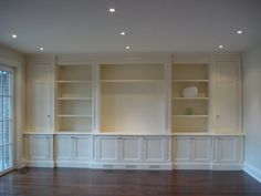 an empty living room with built - in bookshelves and wood flooring is shown