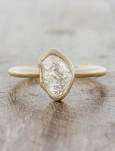 a close up of a ring on a wooden surface with a diamond in the middle