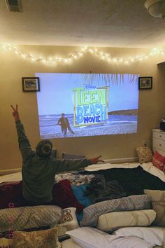 a man sitting on top of a bed in front of a flat screen tv