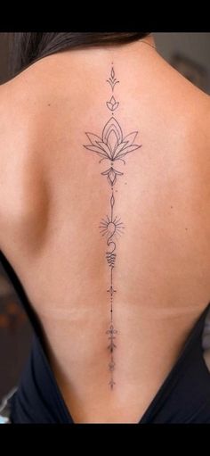 the back of a woman's neck with a flower tattoo on her lower back