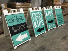 three signs that are on the ground in front of some pallets with boxes behind them