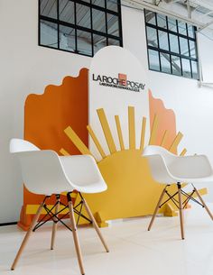 two white chairs sitting next to each other in front of a wall with an advertisement on it