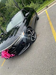 a black car with pink flowers on the hood parked in front of a parking lot