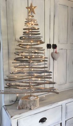 a christmas tree made out of branches and lights on top of a white dresser in a room