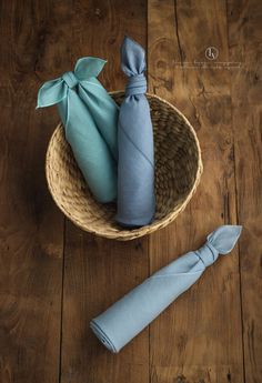 two blue napkins in a woven basket on a wooden floor next to an umbrella