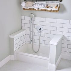 a bathroom with white tile and two baskets on the wall above the bathtub is filled with towels