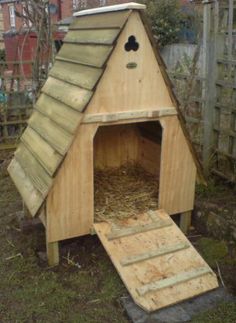 a dog house made out of wood with a ramp leading up to the door and windows