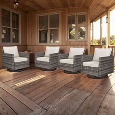 four wicker chairs sitting on top of a wooden deck next to two large windows