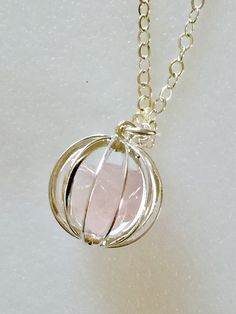 "Lovely gemstone necklace featuring gentle pink polished raw rose quartz nuggets captured inside darling 15 mm vintage cage in plated Sterling silver and suspended from delicate sparkling Sterling silver cable chain with matching spring ring clasp. Necklace available in 16\", 18\", or 20\" lengths. Also available on Sterling silver plated chain with matching lobster claw clasp. Both are lovely. Rose quartz is often called \"Love Stone\". It's energy opens the heart to unconditional love. It is a Silver Round Crystal Necklaces For Valentine's Day, Silver Crystal Necklace For Valentine's Day, Rose Quartz Wire Wrapped Jewelry For Healing, Wire Wrapped Rose Quartz Jewelry For Healing, Rose Quartz Wire Wrapped Necklace As Gift, Wire Wrapped Rose Quartz Necklace Gift, Rose Quartz Round Pendant Crystal Necklace For Gift, Rose Gold Wire Wrapped Round Pendant Jewelry, Silver Rose Quartz Gemstone Jewelry