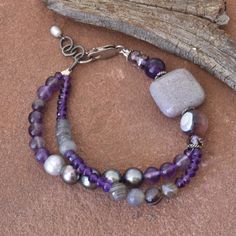 Varying shades of purple, violet, lavender, and gray come together in this beautiful multi strand bracelet. It features natural amethyst, Botswana agate, jasper, freshwater pearls, gray labradorite, and czech glass.   This bracelet has a sterling silver lobster clasp and measures 7 inches with a 1 inch extender chain.  Comes in a gift box, perfect for giving. Bohemian Lavender Beaded Bracelets, Elegant Gray Bracelets With Natural Stones, Bohemian Amethyst Lavender Bracelet, Bohemian Lavender Hand-strung Jewelry, Bohemian Purple Multi-strand Beaded Bracelets, Purple Multi-strand Beaded Bohemian Bracelets, Bohemian Multi-strand Purple Beaded Bracelets, Purple Multi-strand Bohemian Beaded Bracelet, Handmade Purple Multi-strand Bracelets