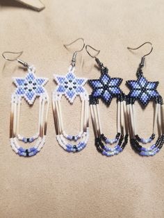 three pairs of beaded earrings are sitting on the floor next to each other and one has an ornament in the shape of a star