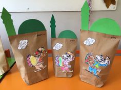 three brown paper bags with cartoon images on them sitting on a table in front of a green wall