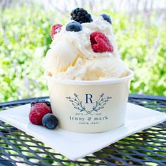 an ice cream sundae with berries and blueberries in it on a plate outside