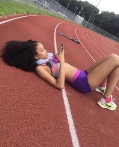 a woman laying on the side of a track while holding a cell phone in her hand