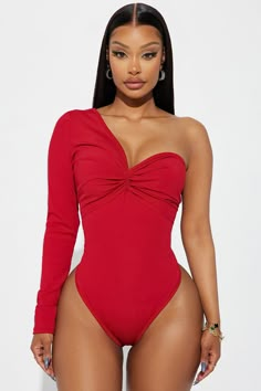 a woman wearing a red one piece swimsuit with long sleeves and an asymmetrical neckline