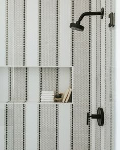 a bathroom with black and white striped wallpaper, shower faucet, and bookshelf