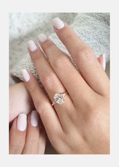 a woman's hand with white manicured nails and an engagement ring